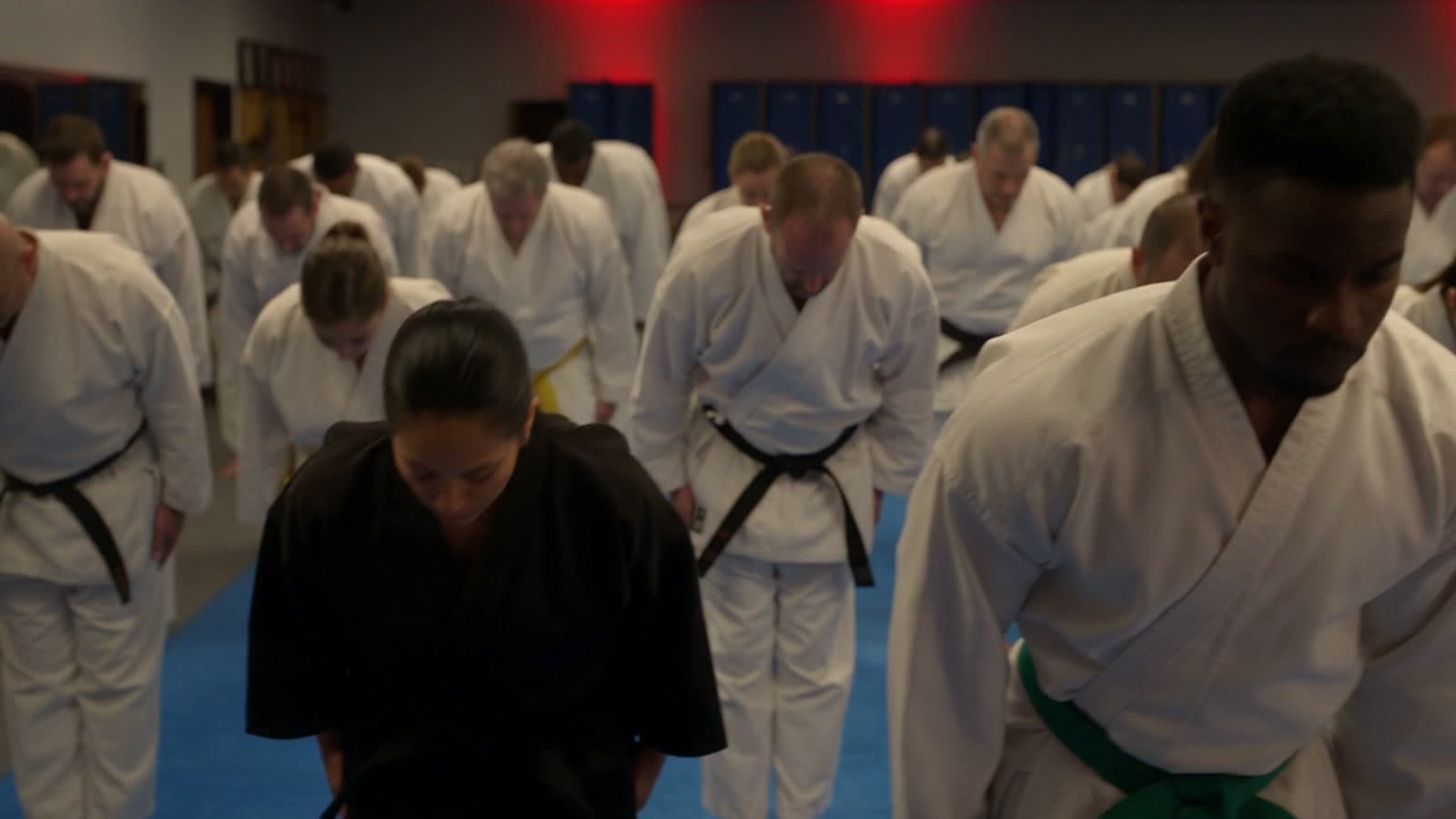 Adult students in white gis bowing together in a martial arts class